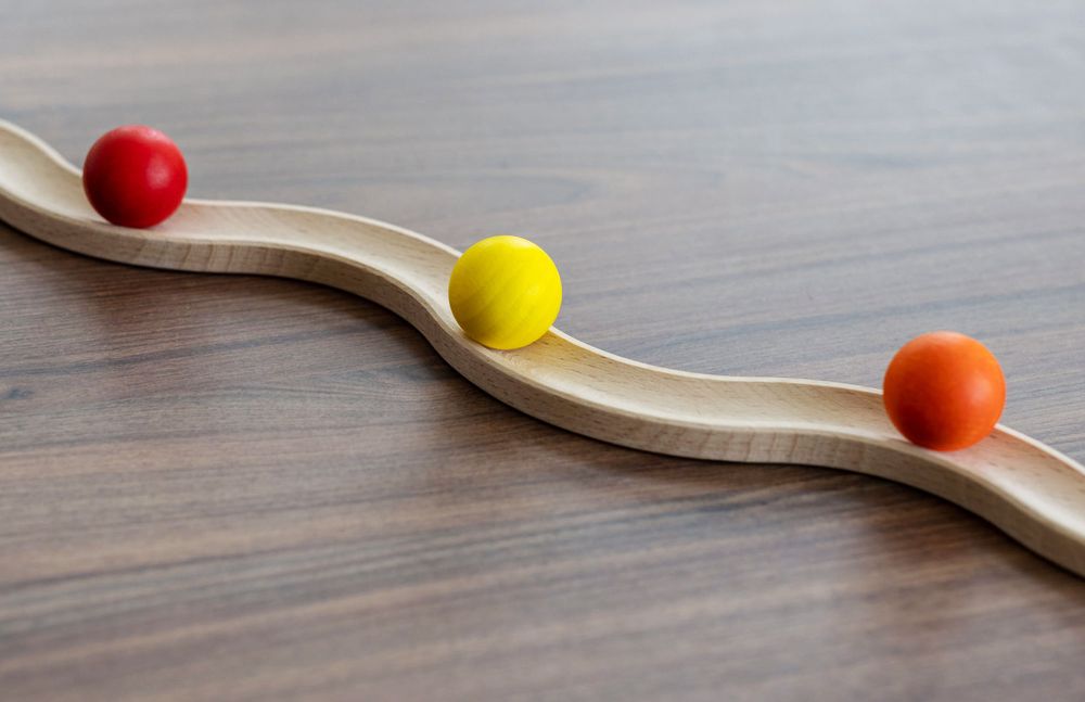 Dekorative Holzwippe mit bunten Kugeln als Symbol für Balance