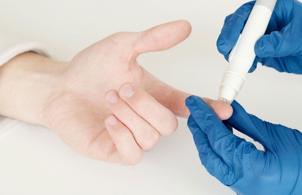 Hand wird mit Lanzette zur Blutzuckermessung am Finger getestet