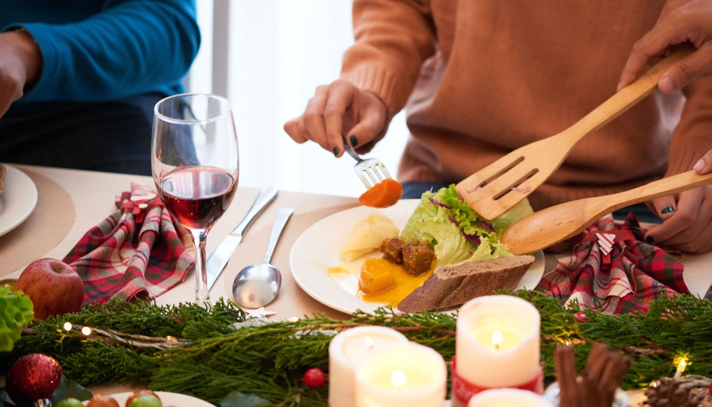 Weihnachtlich gedeckter Tisch, Menschen servieren frischen Salat