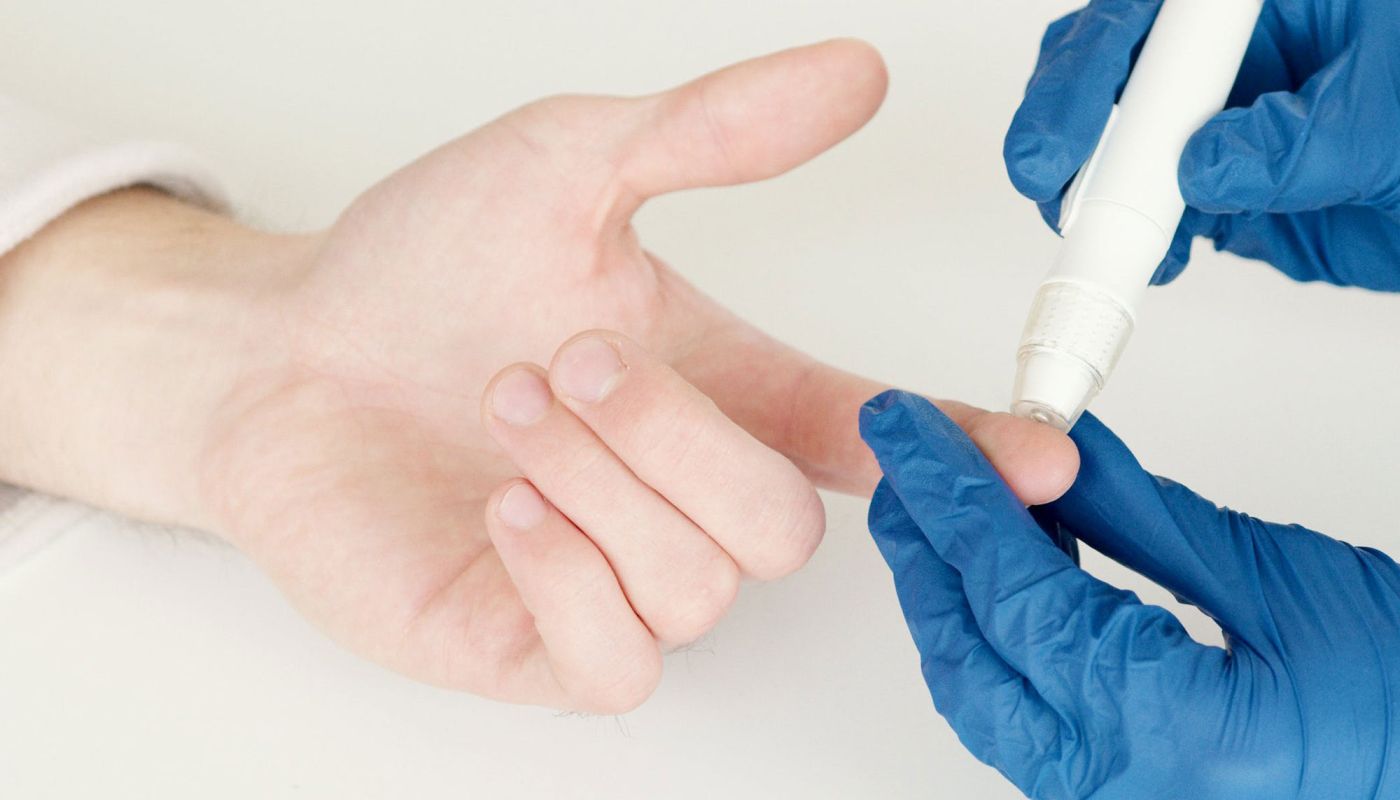 Hand wird mit Lanzette zur Blutzuckermessung am Finger getestet