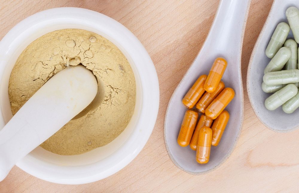 Mörser mit Pulver und Kapseln auf Holzuntergrund