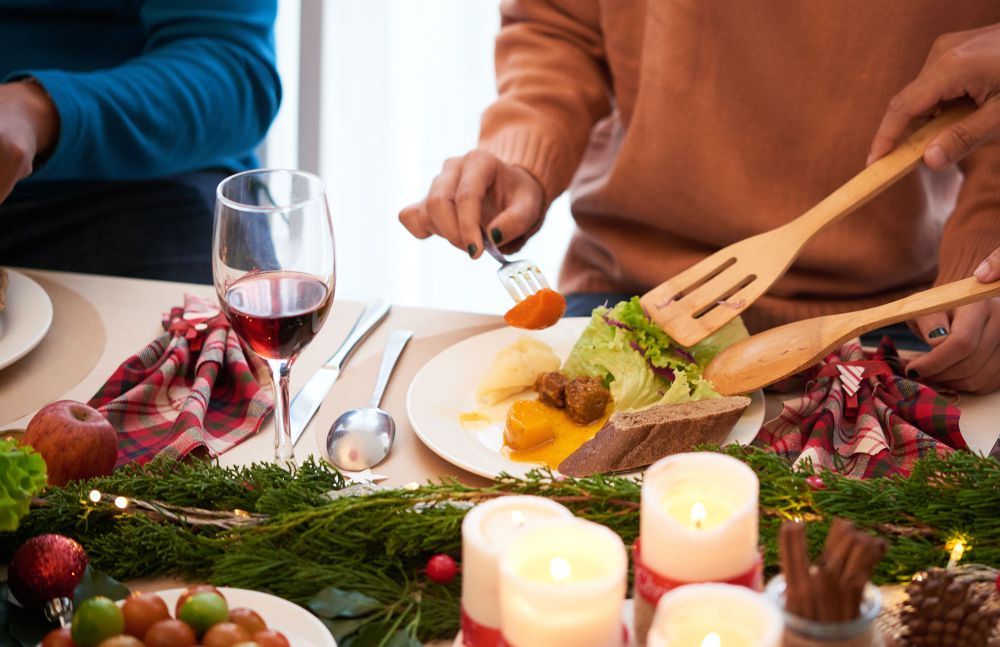 Weihnachtlich gedeckter Tisch, Menschen servieren frischen Salat