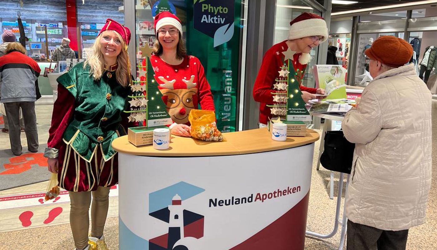 Apothekerinnen im Weihnachtskostüm sammeln Spenden an einem Infostand