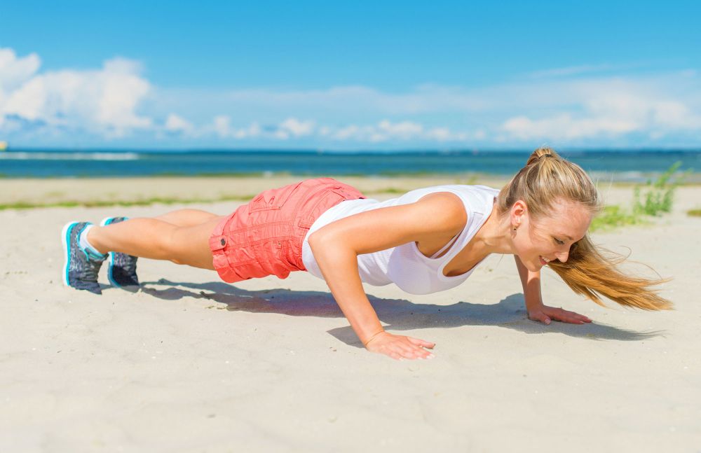 Frau macht Liegestütze am Strand