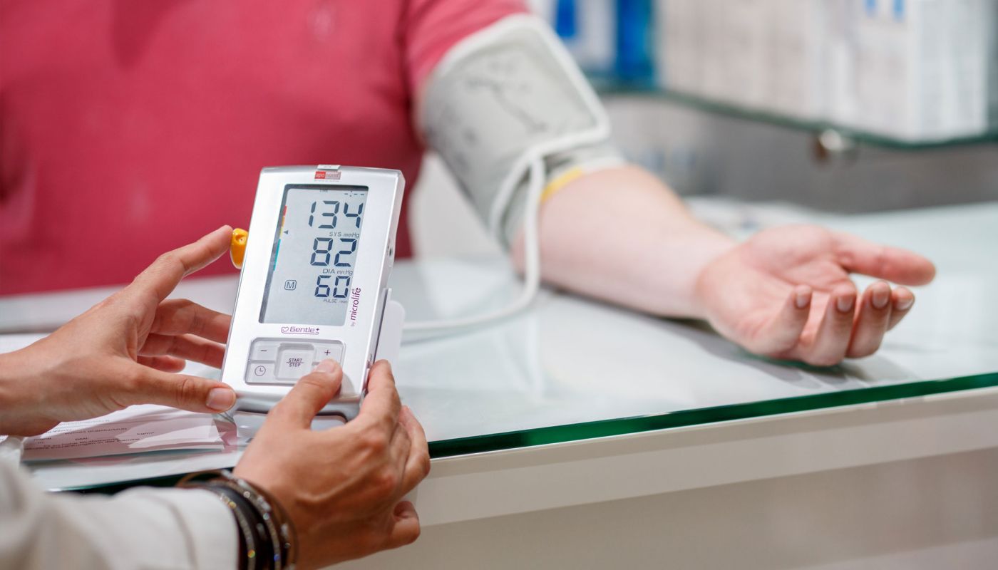 Blutdruckmessgerät zeigt Werte, Apothekerin erklärt Messung
