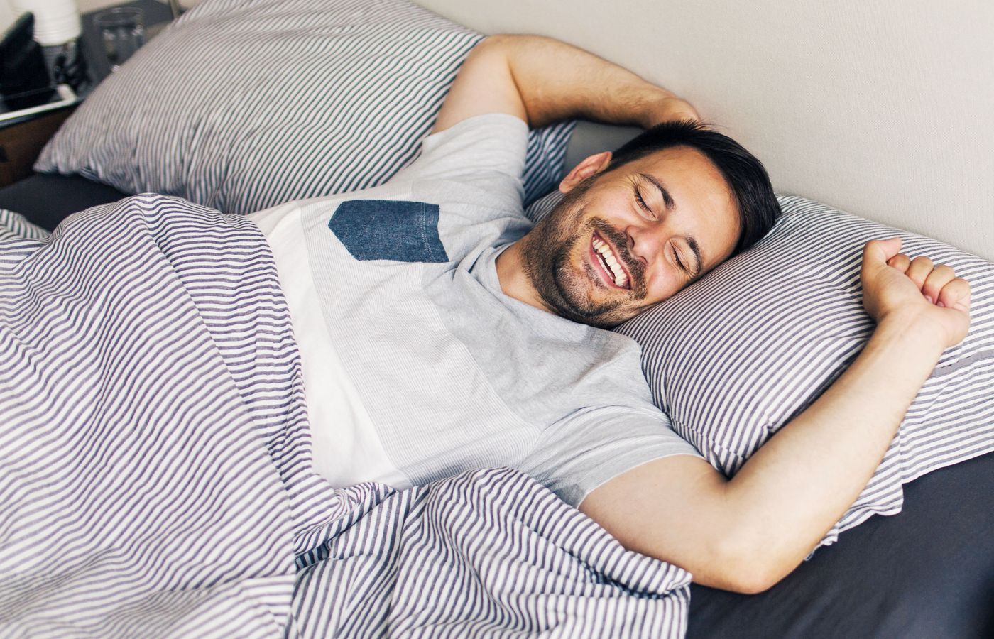 Mann liegt lächelnd schlafend im Bett