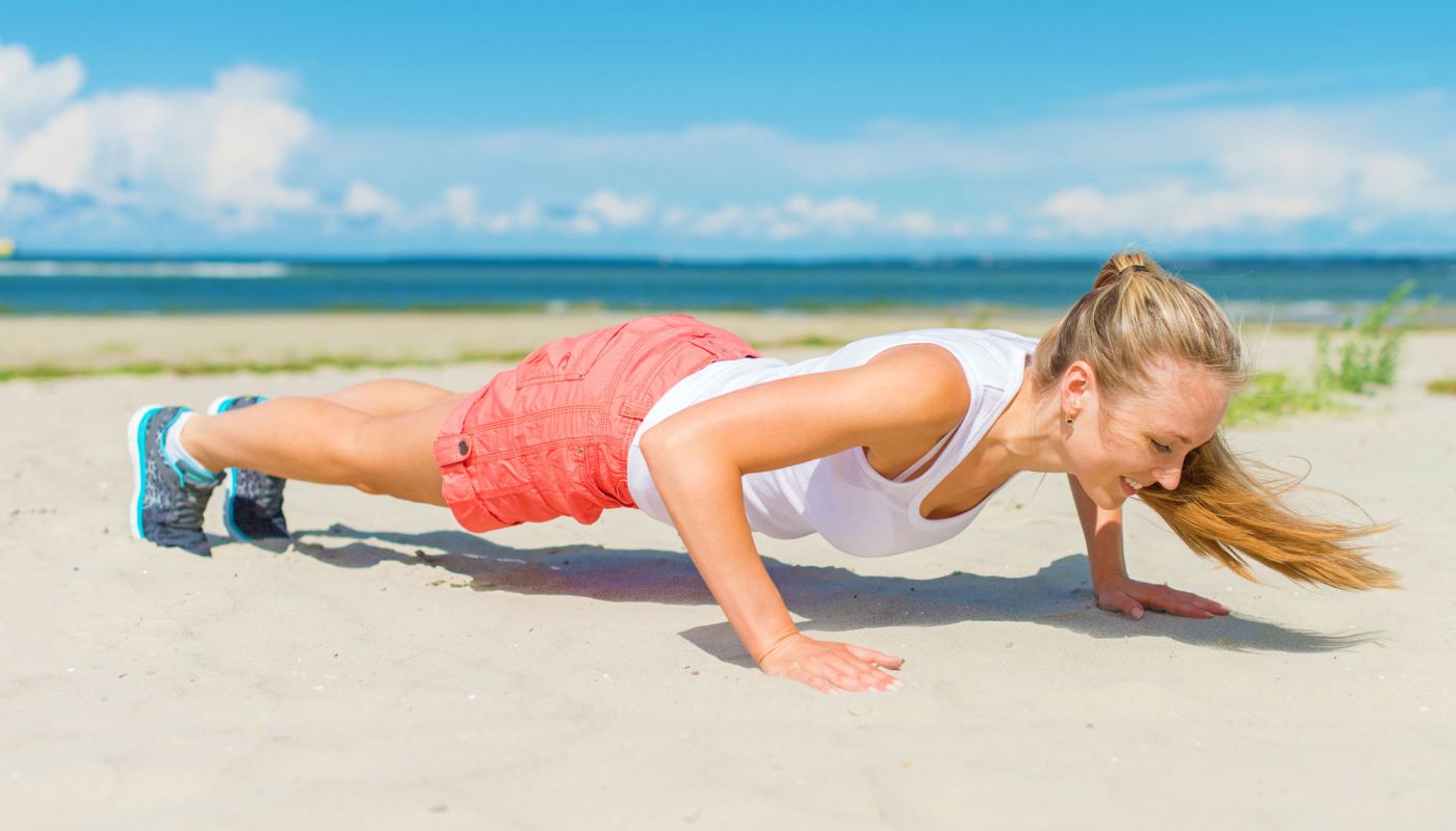 Frau macht Liegestütze am Strand