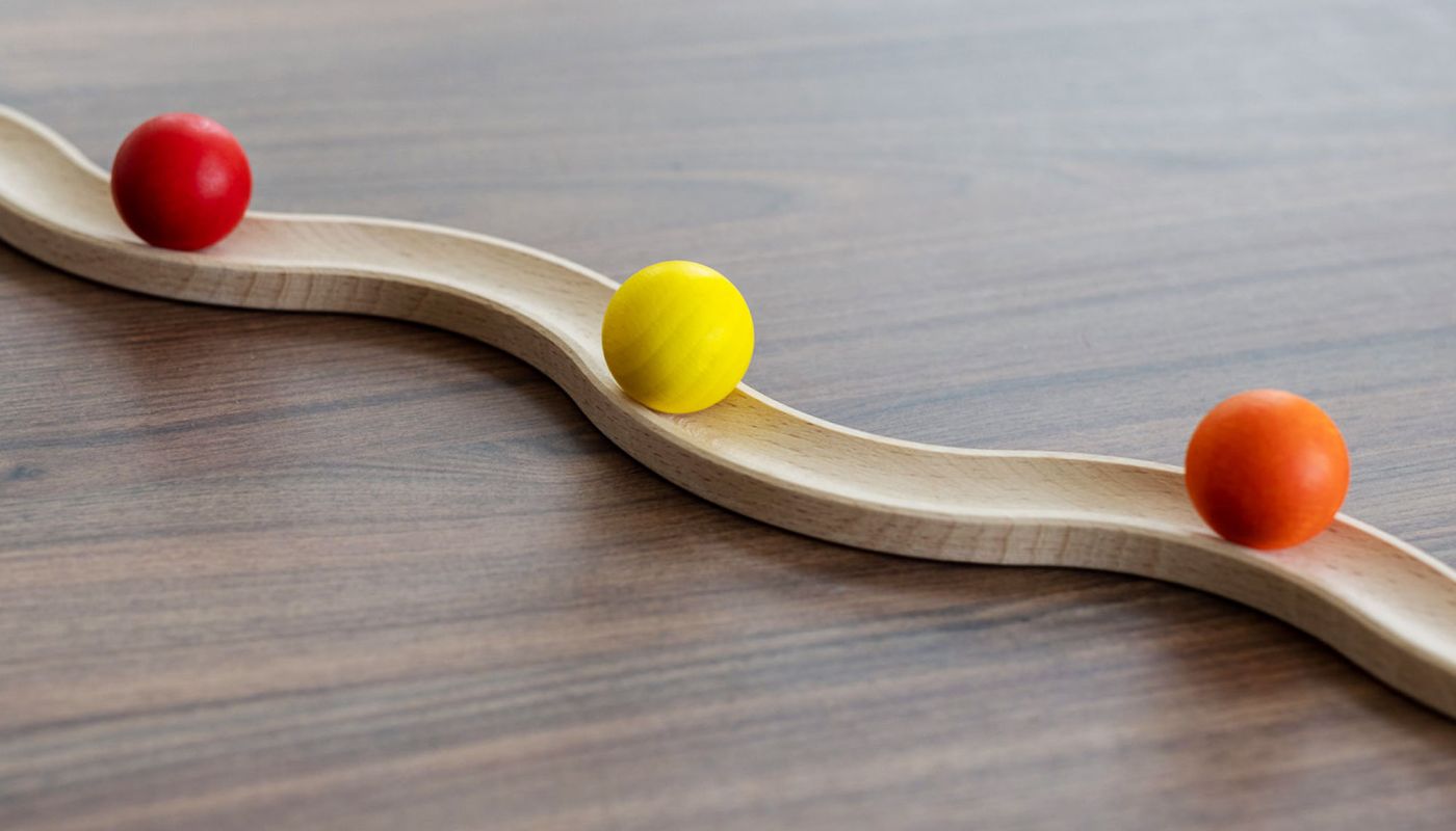 Dekorative Holzwippe mit bunten Kugeln als Symbol für Balance