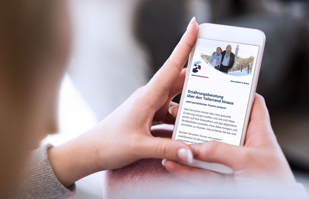 Hand hält Smartphone mit Newsletter der Neuland Apotheken