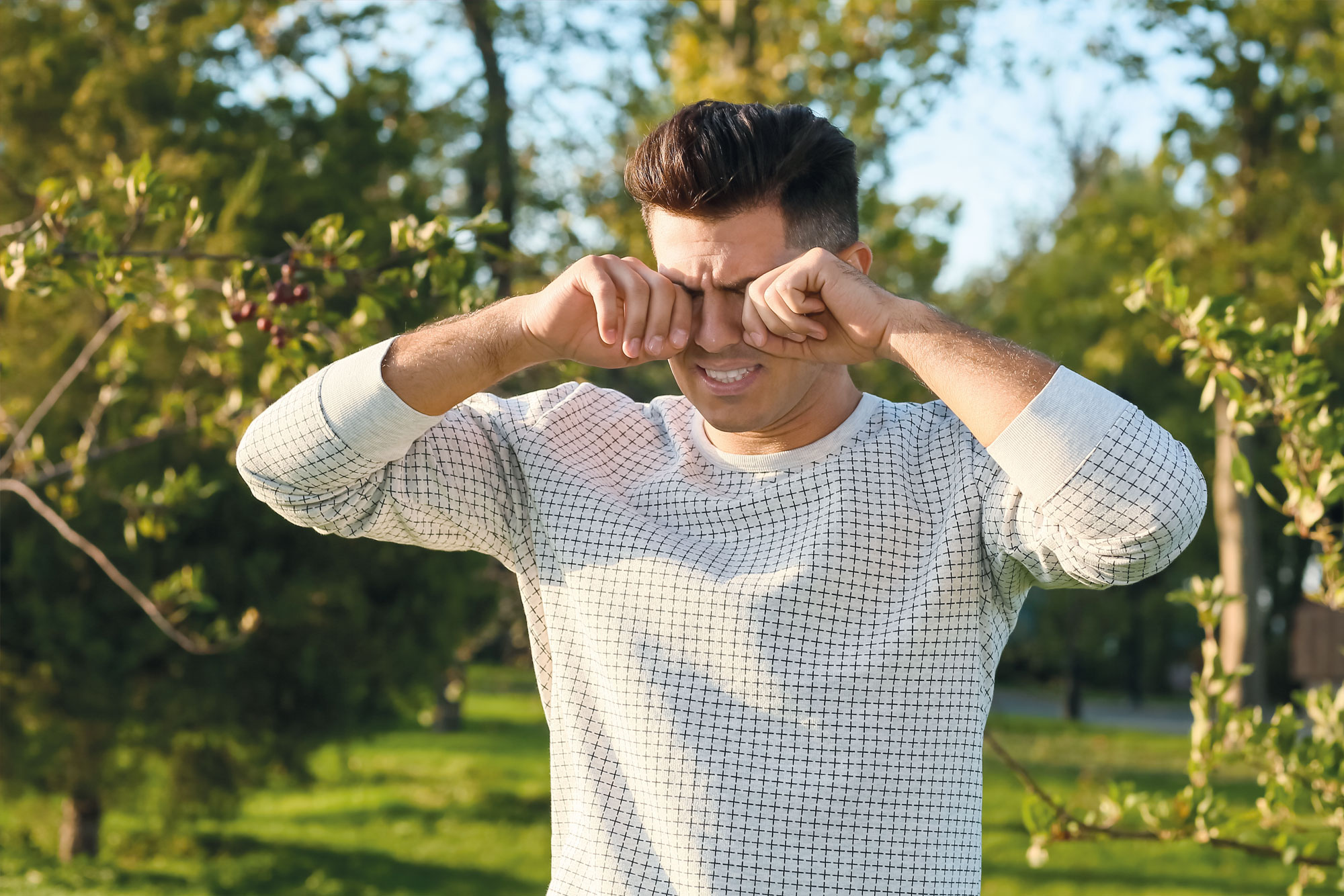 Mann reibt sich die Augen im Frühling wegen Pollenallergie