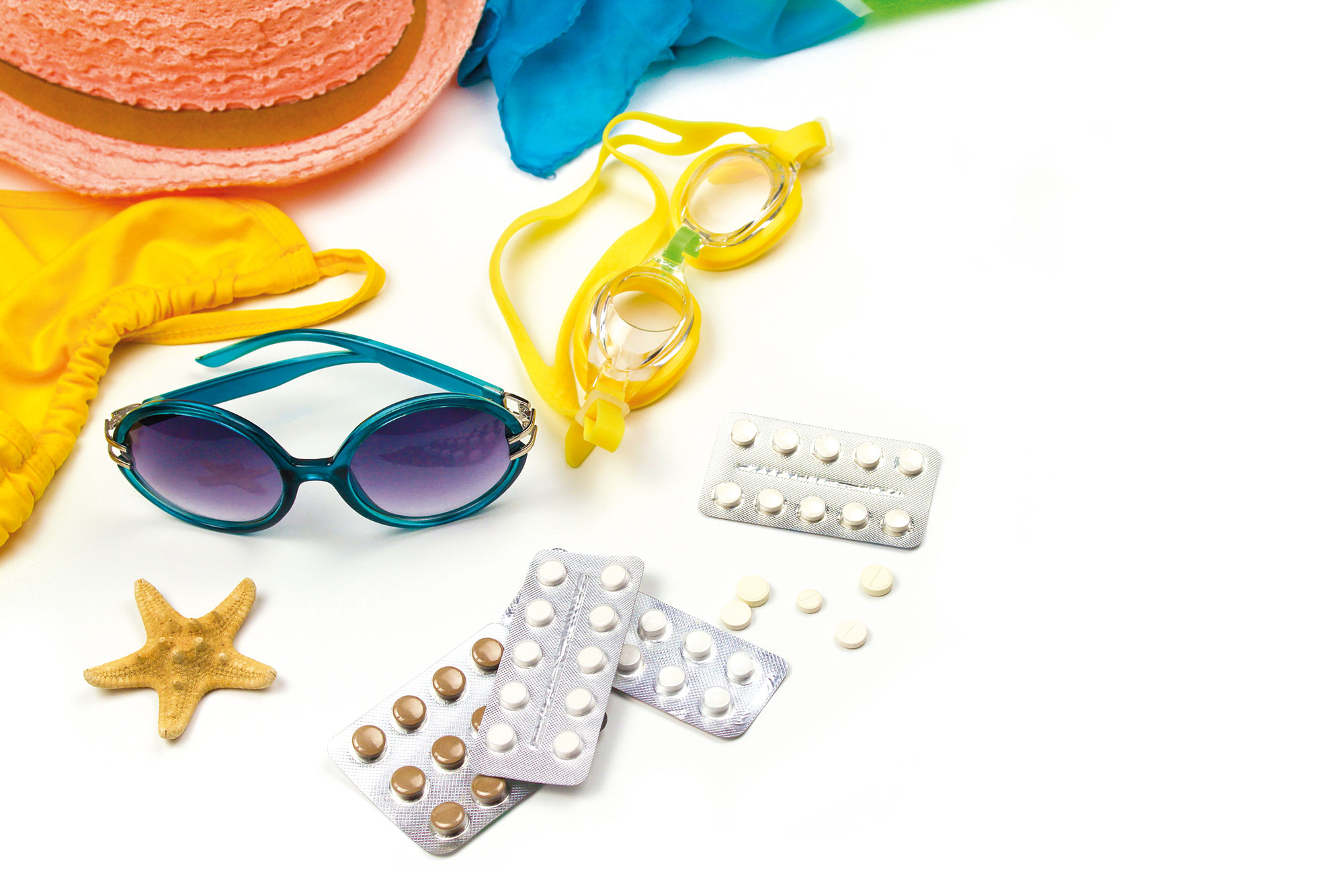 Urlaubsgegenstände wie Sonnenbrille, Bikini, Medikamente auf Tisch