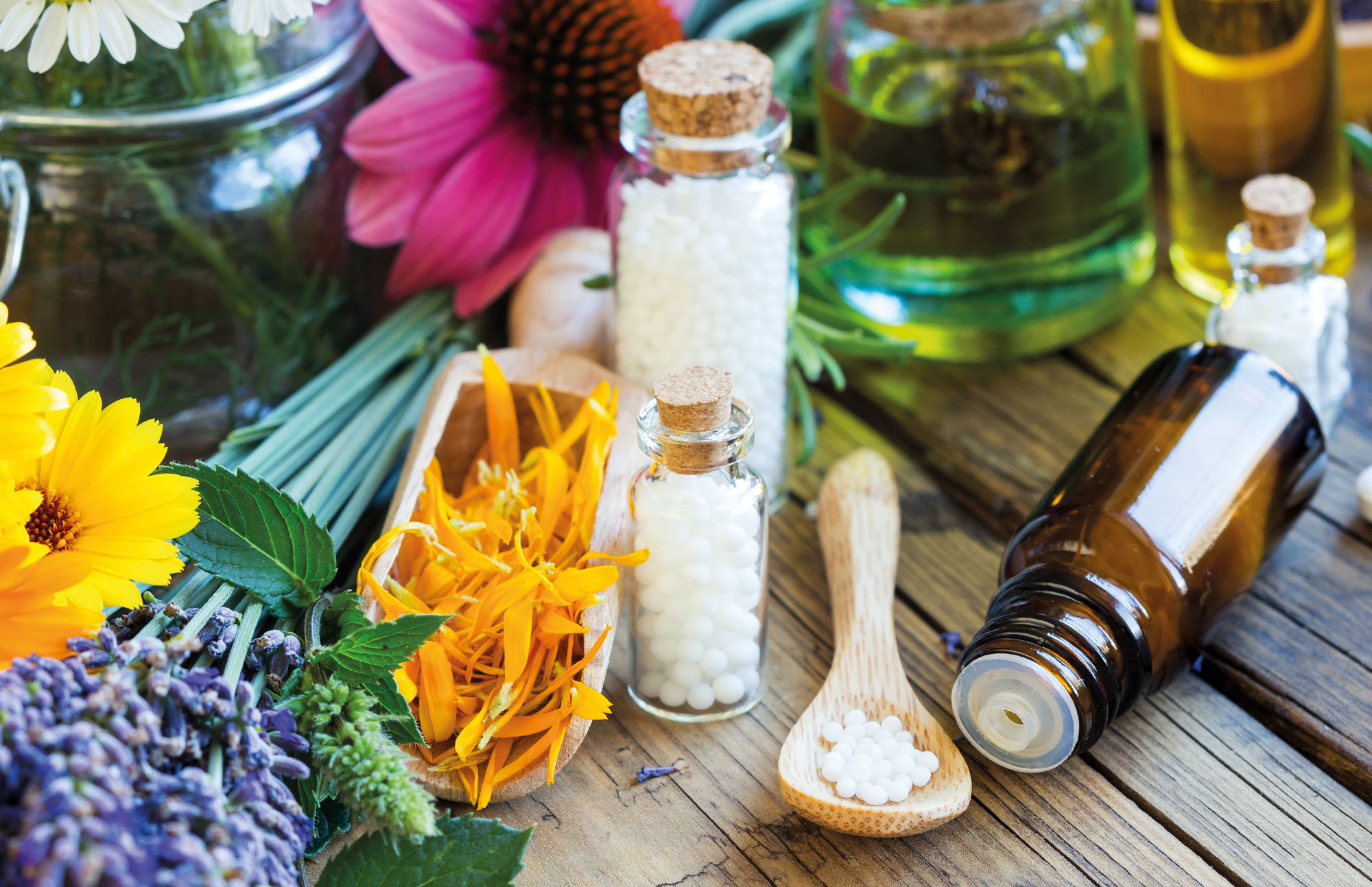Naturheilmittel wie Blüten und ätherische Öle auf Holztisch