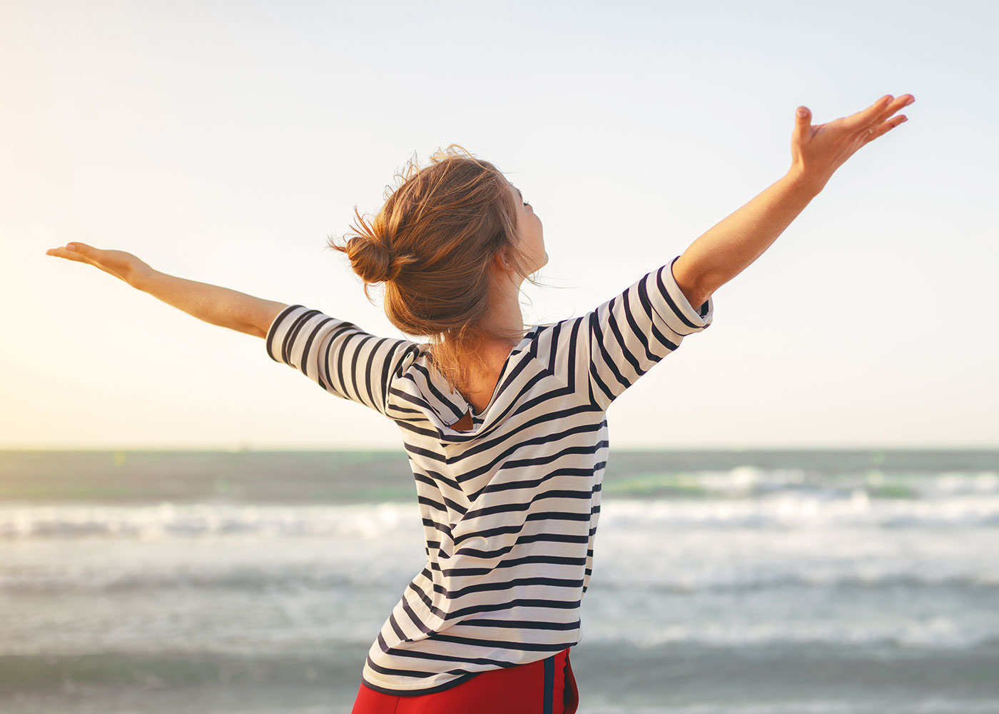 Stellenanzeige für Apotheker (m/w/d) – Frau genießt die Meeresluft am Strand, symbolisch für Work-Life-Balance bei den Neuland Apotheken.